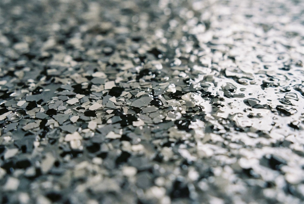 Illustration of a close-up of gray, black, and white decorative flakes under a glossy clear topcoat